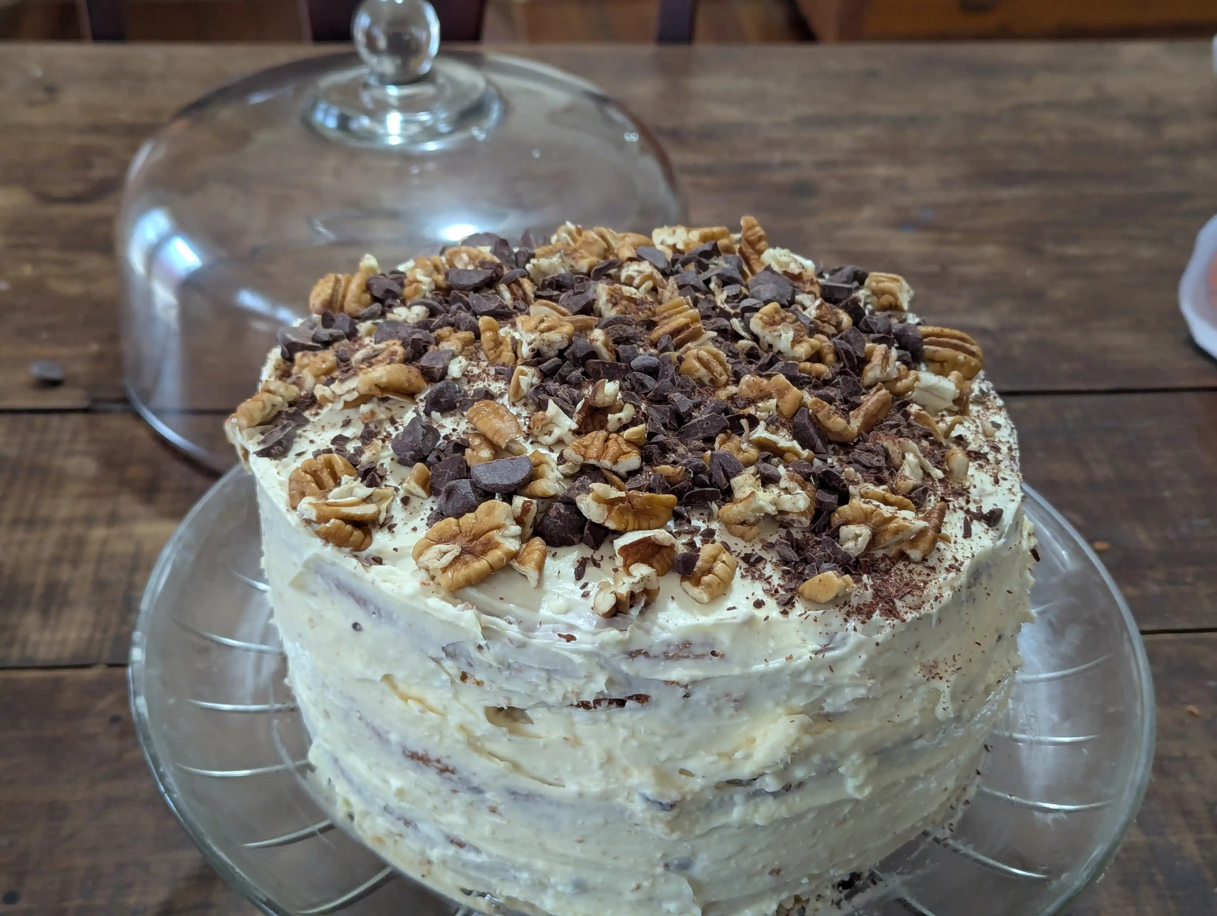 Italian cream cake garnished with chocolate and chopped pecans.