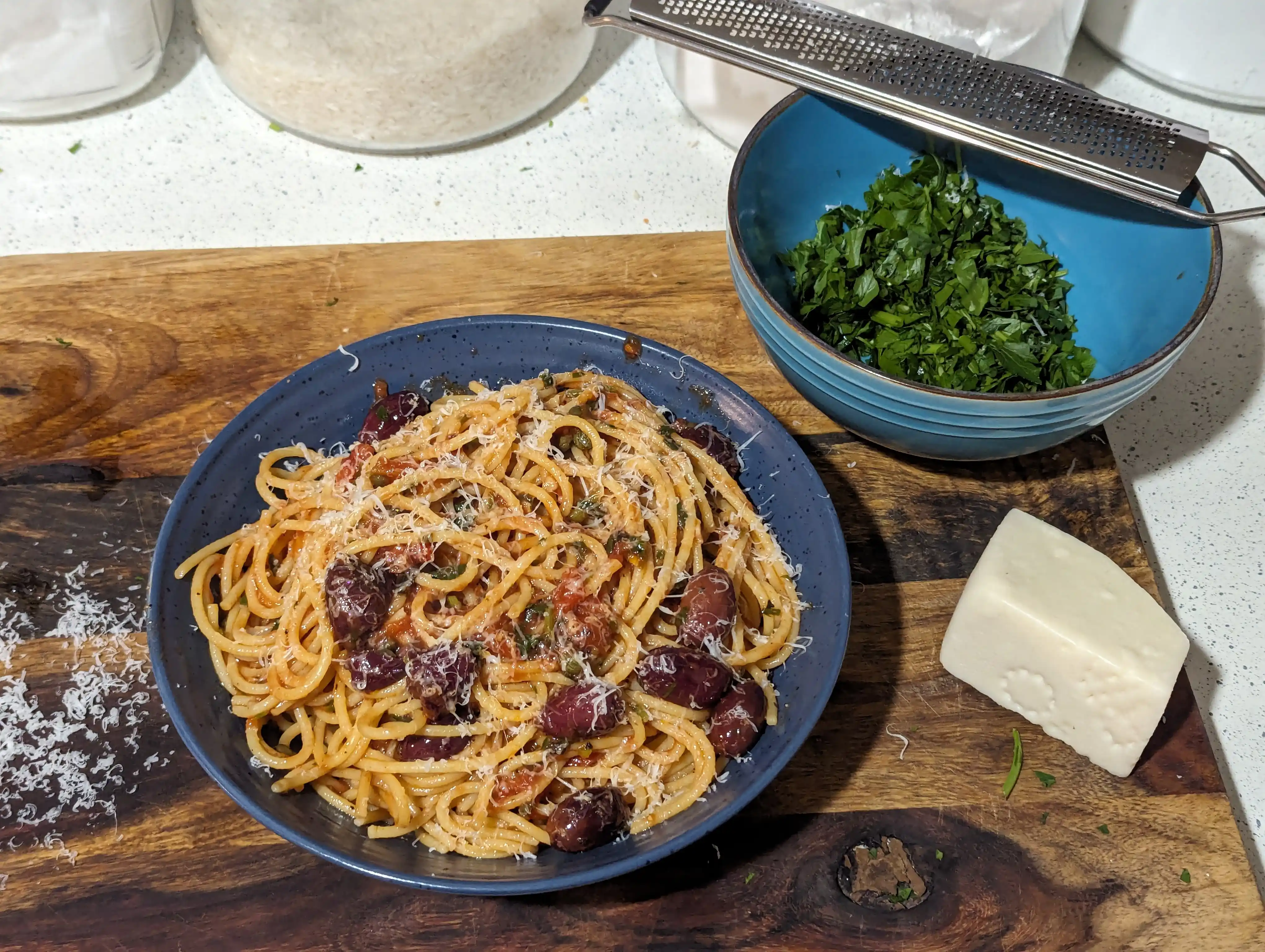 Bowl of spaghetti alla puttanesca garnished with pecorino romano