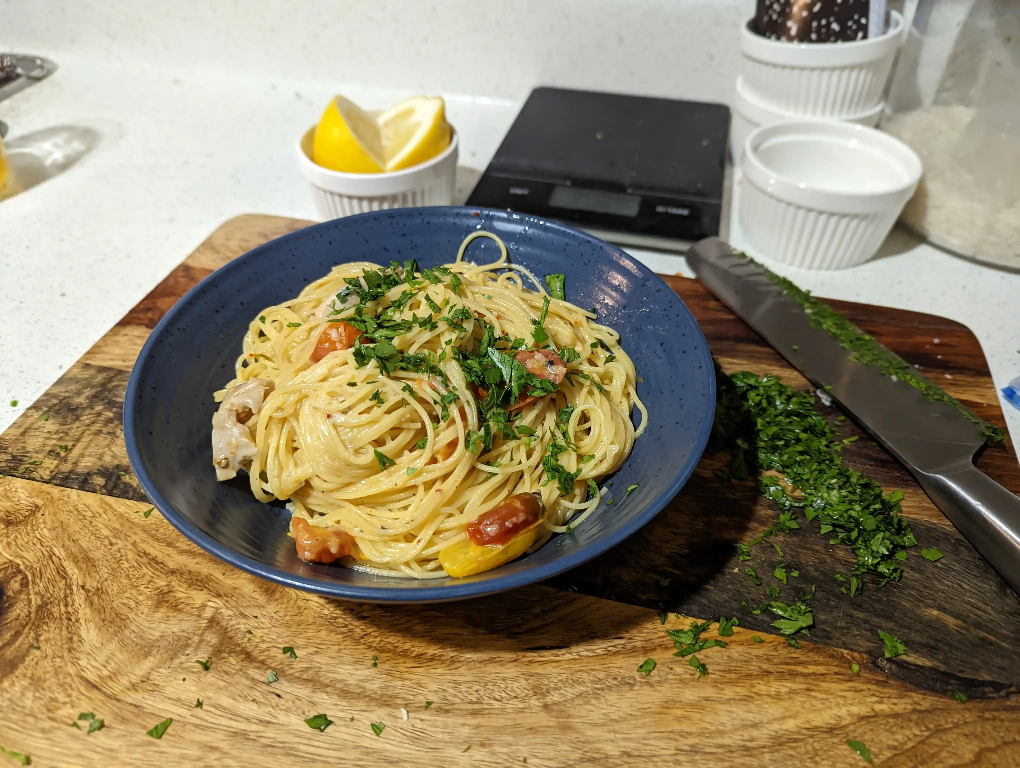 bowl of spaghetti tossed in white wine sauce and garnished with lemon and parsley